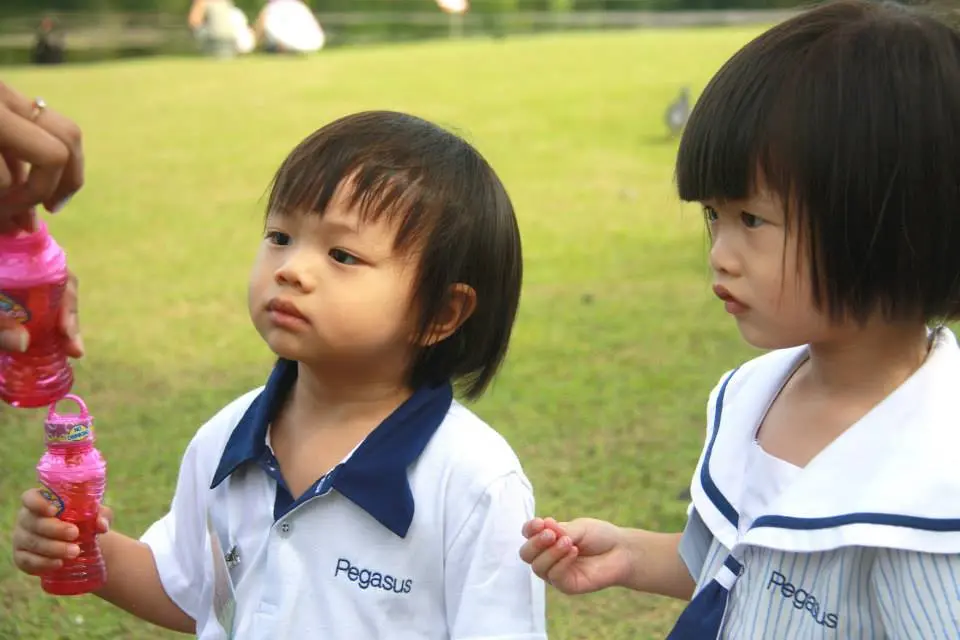 两名幼儿园的孩子在户外拿着泡泡容器。