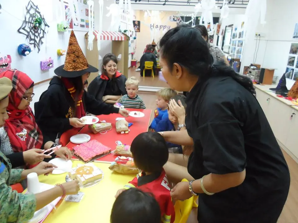 Children and adults gathered around tables during a Halloween activity.