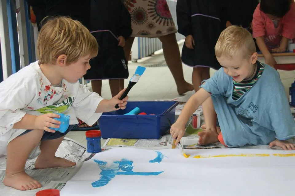 Children exploring collaborative floor painting during a Reggio-inspired art activity at Pegasus