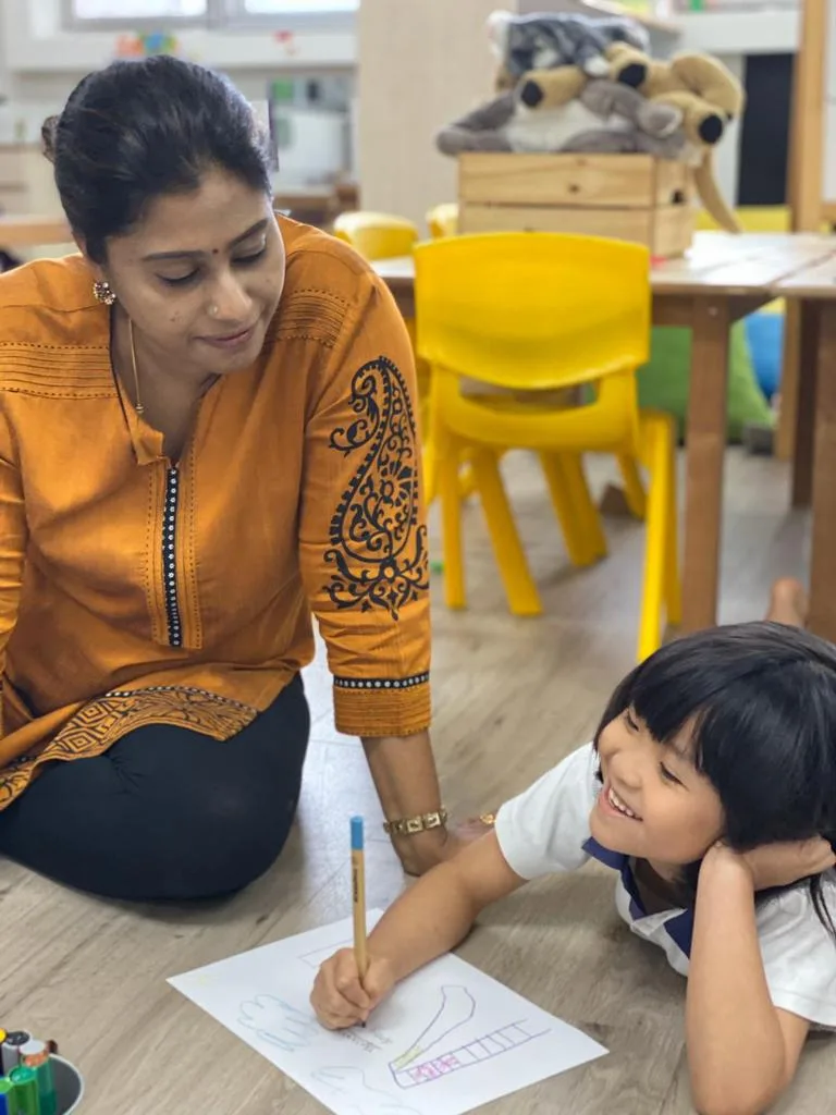 A teacher guiding a Nursery child during a drawing activity at Pegasus