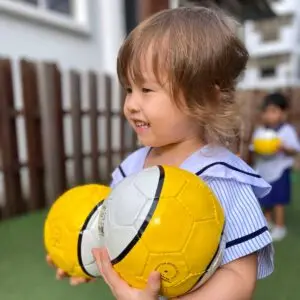 プリスクールの活動中に黄色いサッカーボールを持つナーサリー1の子ども