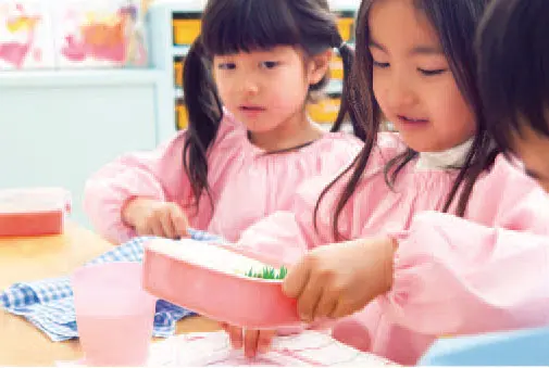幼儿们围坐在幼儿园午餐桌前一起用餐